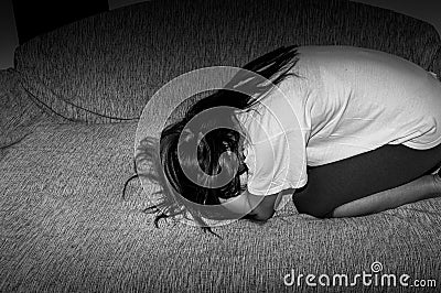 Crying woman abused as young feeling depressed and miserable while she sitting alone in her room Stock Photo