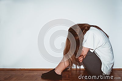 Crying woman abused as young feeling depressed and miserable while she sitting alone in her room Stock Photo