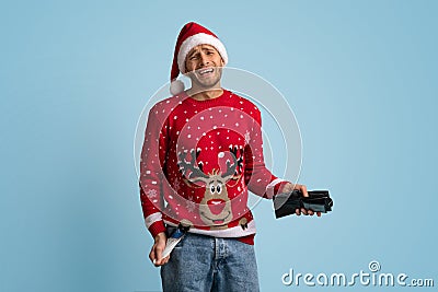 Crying Young Man In Santa Hat Showing Empty Wallet And Pocket Stock Photo
