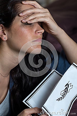 Crying young woman holding obituary Stock Photo