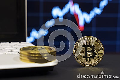 A crypto currency symbol bitcoin close to laptop with graphic on the background Stock Photo