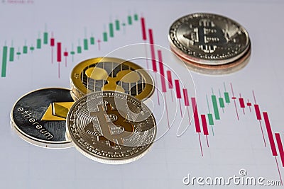 Cryptocurrency coins over trading candles graphic screen; Bitcoin, Ethereum and Ripple coins Editorial Stock Photo