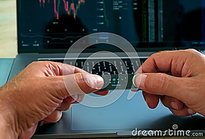 Cryptocurrency investor using crypto hardware wallet to protect his value transaction. Laptop screen showing crypto market graph c Stock Photo