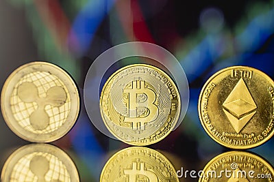 Cryptocyrrency and virtual money concept. Golded bitcoin, ethereum and ripple coins with chart of growing and falling Editorial Stock Photo