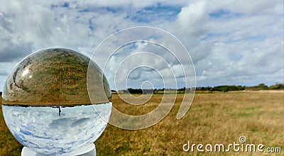 Crystal ball with the flat landscape of the North Sea island Sylt with a lighthouse Stock Photo