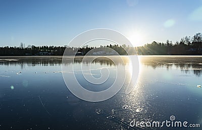 Crystal clear frozen lake in Northern Sweden - ice like big mirror. Low sun lights with warm light at very cold winter day Stock Photo