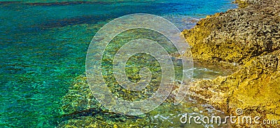 Crystal clear turquoise water near yellow rock shore Stock Photo