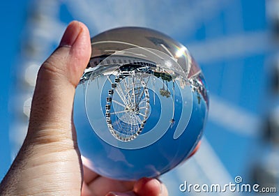 Crystal glass ball in male`s hand with a ferris wheel insid Stock Photo