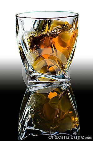 Crystal glass with curved edges with old Scotch whiskey and pieces of ice. Stock Photo