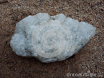 Crystal stone on the sand, textured background. natural stone, rare semiprecious. wallpaper, sea ,ocean. Stock Photo