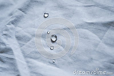 Crystal water droplets shining in light on white fabric drapery with folds Stock Photo