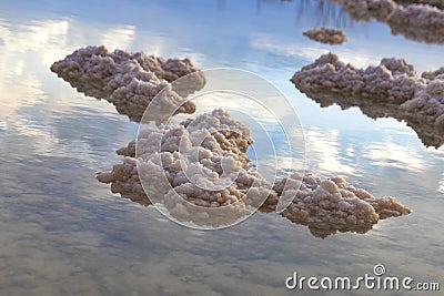Crystals of mineral salts in the waters of the Dead Sea with the sky with clouds reflected in them Stock Photo