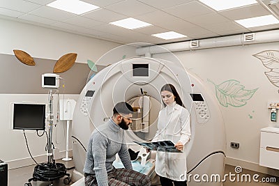 CT Doctor consulting patient and showing x-ray head scan to patient in computed tomography room. CT scan radiologist Stock Photo