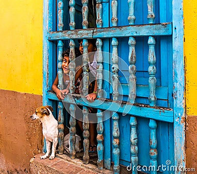 CUBA, TRINIDAD. June 2016: Two children looking out of the window of their house in Trinidad, also a dog is at the window. Editorial Stock Photo