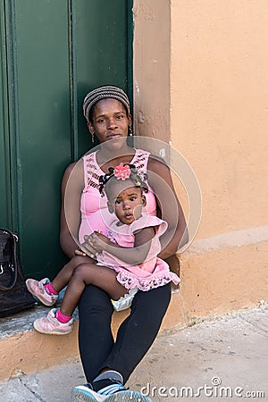 Cuban mother with cute little toddler girl resting in front of frontdoor. Editorial Stock Photo