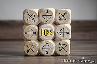 Cubes and dice with arrow and bow icon showing the word idea - idee, metaphor goal or target Stock Photo