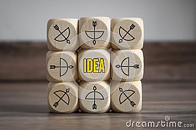 Cubes and dice with arrow and bow icon showing the word idea - idee, metaphor goal or target Stock Photo