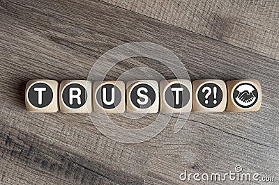 Cubes and dice on wooden background showing the words trust and handshake icon Stock Photo