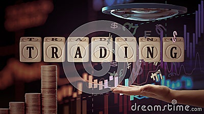 Cubes with the inscription Trading on the background of a hand, flying currency symbols, price charts, columns of coins Stock Photo