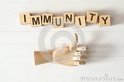 Cubes with word Immunity and mannequin hand showing thumb up gesture on white wooden table, flat lay Stock Photo