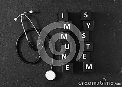 Cubes with words Immune System and stethoscope on black table, flat lay Stock Photo