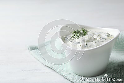 Cucumber sauce in ceramic bowl on wooden background, space for text Stock Photo