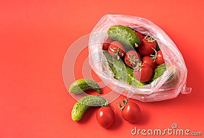 Cucumbers and tomatoes in plastic bag on blue background. Stop using artificial food storage bags concept Stock Photo