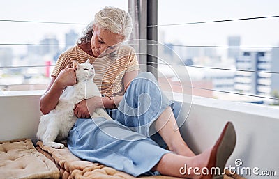 Cuddling with her feline friend. an attractive senior woman cuddling with her cat while relaxing on the balcony at home. Stock Photo