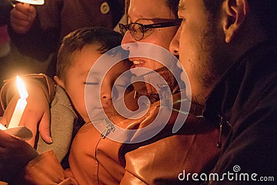 Mother holds sleeping child and candle for Festival de Luzes Fe Editorial Stock Photo