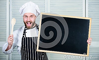 Culinary training. Chief cook teaching master class in cooking school. Man holding wooden spoon and blackboard. Master Stock Photo