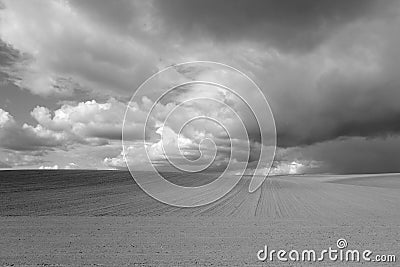 Cultivated agricultural field and cloudy sky. Black and white Stock Photo