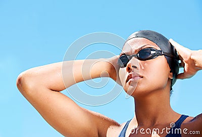 Cultivating a winners mindset. Determined young female swimmer adjusting her swimming goggles. Stock Photo