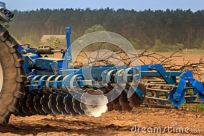 cultivator on ground road by ploughed field against village Stock Photo