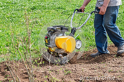 Cultivator for tillage in the garden,motor cultivator. Man Farmer plows the land with a cultivator Stock Photo