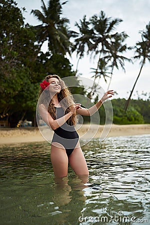 Woman performs hula dance in sea, tropical backdrop, flower in hair, travel, Hawaiian culture, serene beach holiday Stock Photo