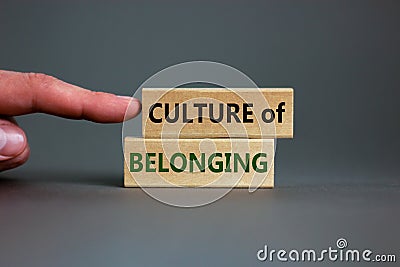 Culture of belonging symbol. Wooden blocks with words `culture of belonging` on beautiful grey background. Businessman hand. Stock Photo