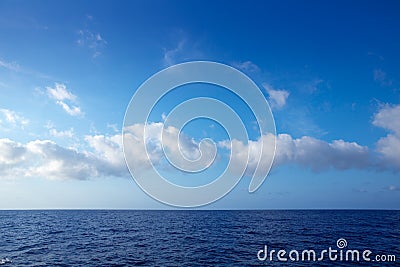 Cumulus clouds in blue sky over water horizon Stock Photo