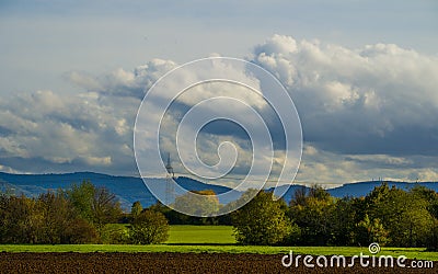 Cumulus rain clouds over landscape with arable, trees and hills Stock Photo