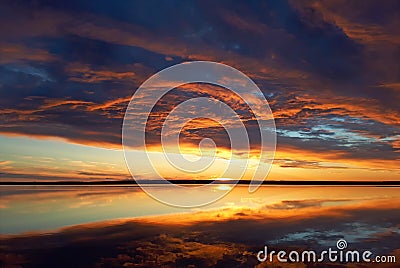 Cumulus sunset clouds with sun setting down. Fiery orange sunset sky. Beautiful sky. Stock Photo