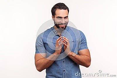 Cunful sneaky man in blue shirt gesticulating with fingers planning devious tricks and cheats, scheming prank, having fun Stock Photo