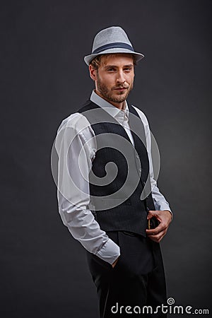 A cunning fellow, in a retro suit and a hat, stands with a steadfast gaze. Stock Photo