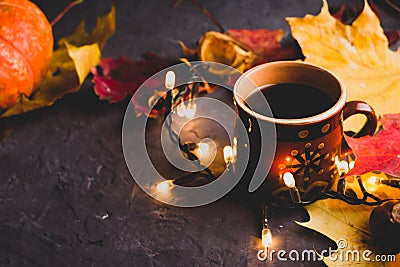 Cup of black coffee, autumn maple leaves and lights on dark background. Cozy autumn seasonal background. Stock Photo