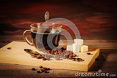 A cup of black coffee with lumps of sugar and coffee beans Stock Photo