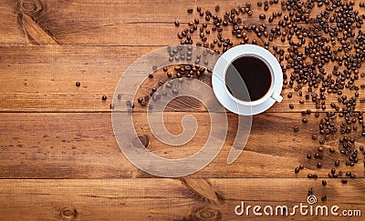 Cup of black morning coffee and cofee beans scattered on brown wooden table, espresso dark coffe aroma cafe shop background, warm Stock Photo