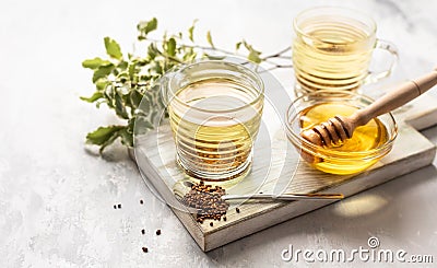 Cup with buckwheat tea, granules and honey, light grey background. Superfood Taiwan Ku Qiao buckwheat tea and grits of tartary Stock Photo