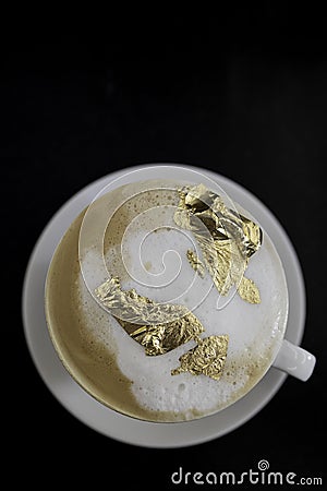 Cup of cappuccino with a golden foam, luxury drink concept. Stock Photo