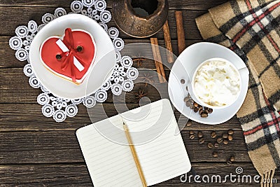 Cup of cappuccino, heart shaped cookies width message, notebook, pencil and coffee pots on a brown wooden table Stock Photo