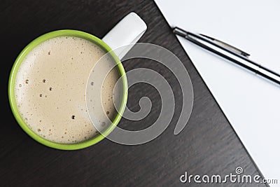 Cup of cappuccino, paper notepad, pen, and on the wooden background. Stock Photo