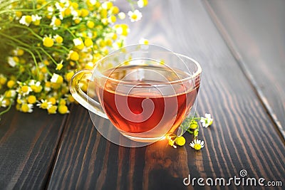 Cup of chamomile tea and a bunch of chamomile flowers on the table. Stock Photo