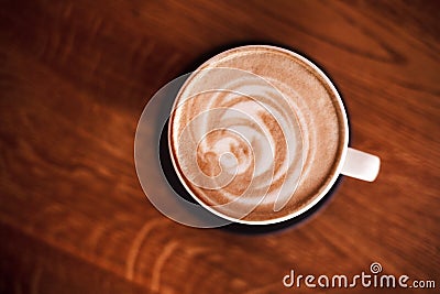 A cup of coffee art in a white cup on wooden background. Stock Photo